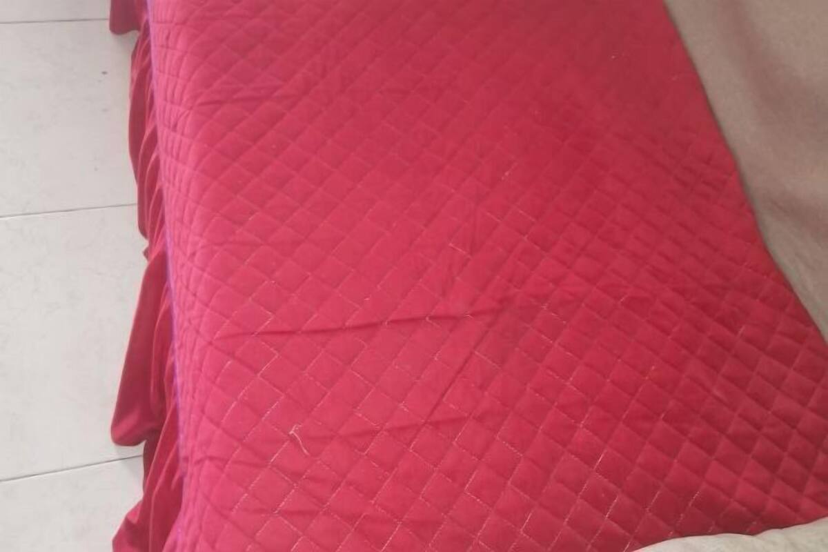 A red quilted bedspread on a bed.