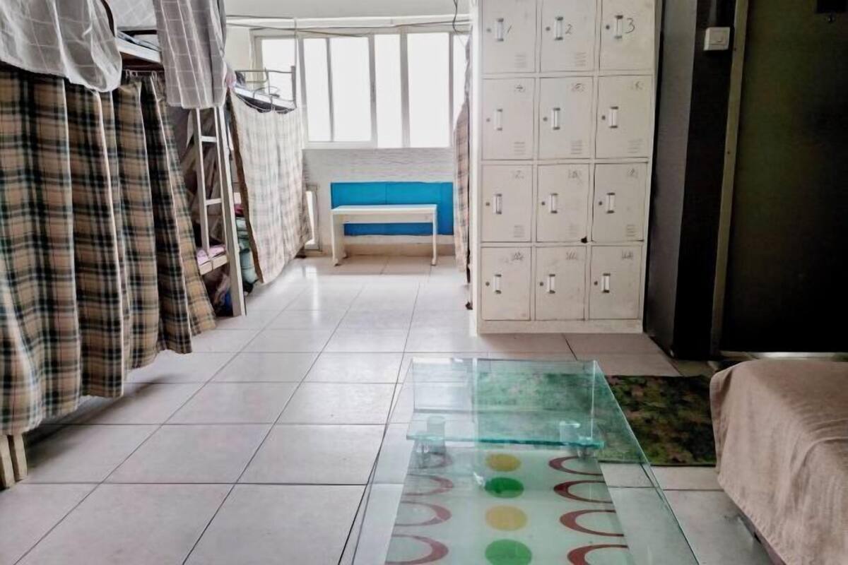 A room with a bunk bed, a bench, a locker area, and a glass table with colorful circles.
