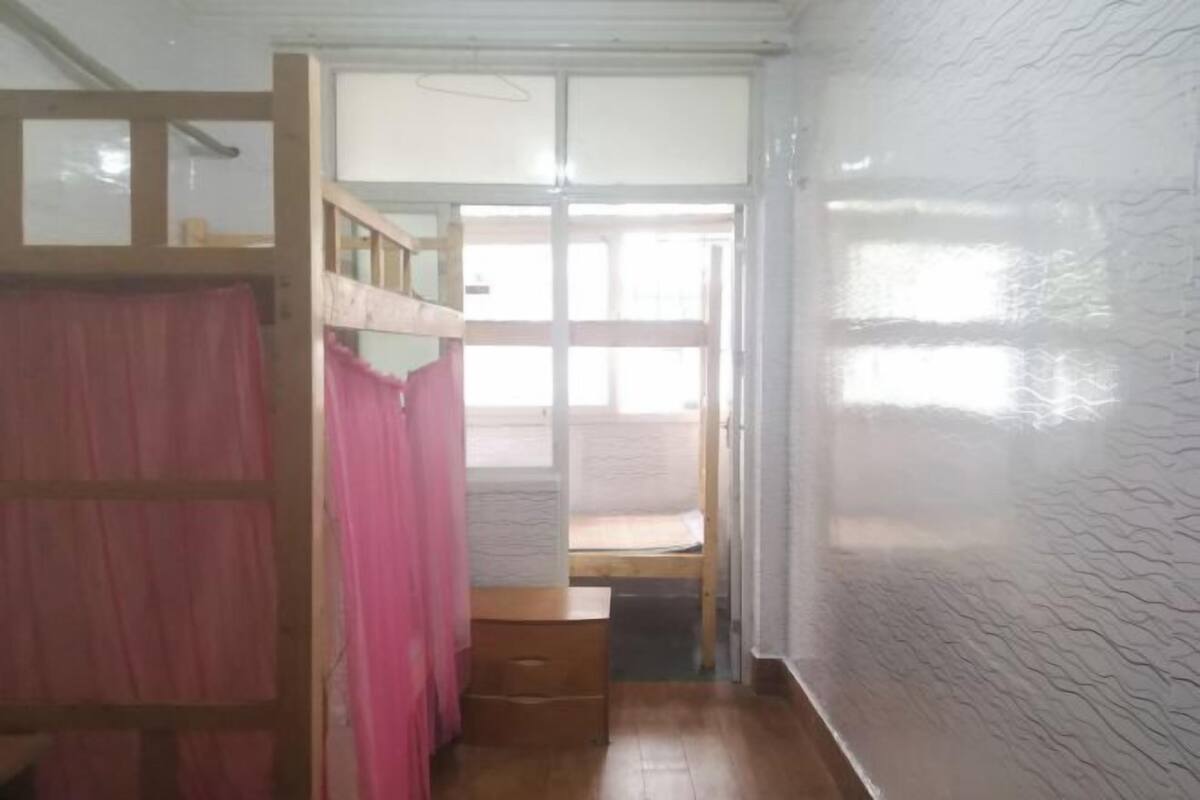 A room with a bunk bed, a small wooden desk, and a sliding door leading to an outdoor area.
