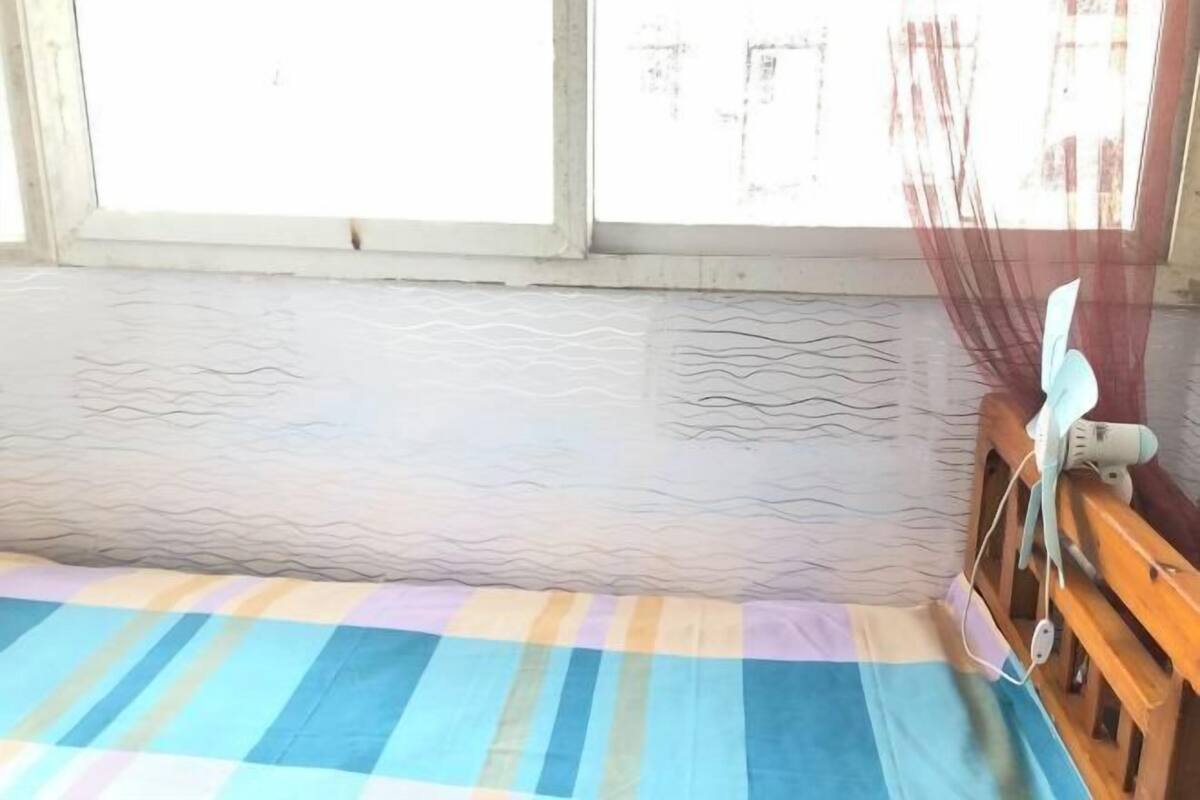 A room with a bed, a window with a view, and a bedside table with a lamp.