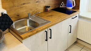 Une cuisine avec un plan de travail en bois, un évier en acier inoxydable et des armoires blanches.