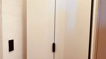 A wardrobe with a vertical handle and multiple drawers.