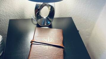 Una taula petita amb una làmpada, un llibre encuadernat en cuir i un objecte metàl·lic a la part superior.