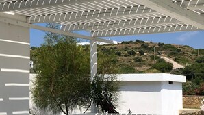A white pergola structure with a view of a hillside and a building in the background. - Villa Omega in Kokkali, Leros (Kokkali)