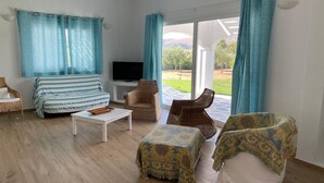 A living room with a sofa, armchairs, a coffee table, and a TV. - Villa Omega in Kokkali, Leros (Kokkali)