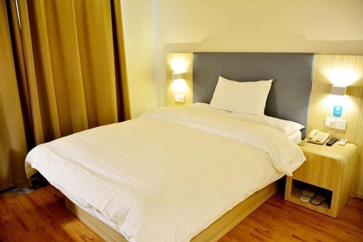 Une chambre d’hôtel avec un lit, des lampes de chevet, une table de chevet avec un téléphone et une lampe, et un plancher en bois.