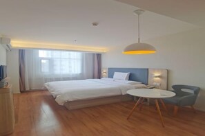 Una habitación de hotel moderna con una cama grande, una mesita de noche y una pequeña mesa redonda con sillas.
