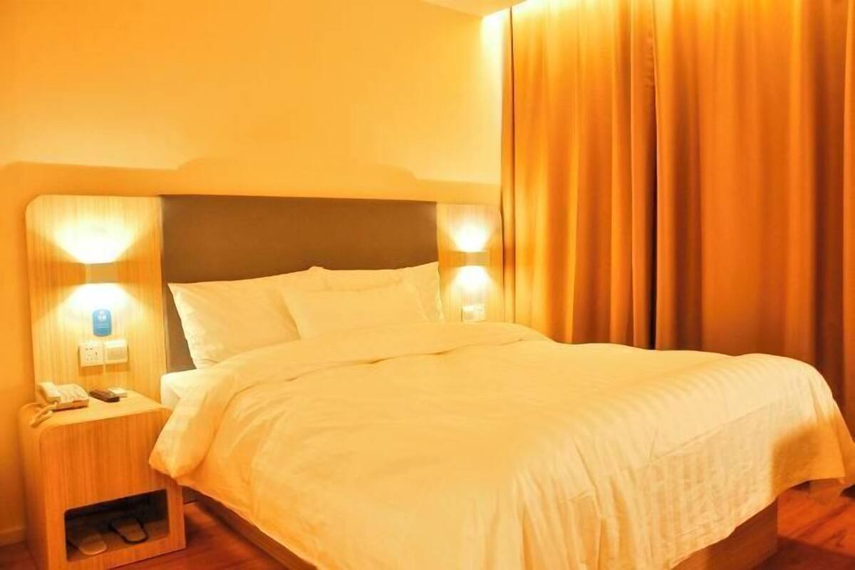 Une chambre d’hôtel avec un lit, une table de chevet avec un téléphone et des rideaux.