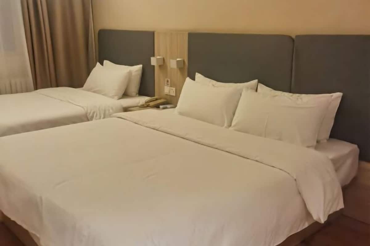 Une chambre d’hôtel avec deux lits, chacun doté de draps blancs et d’une tête de lit.