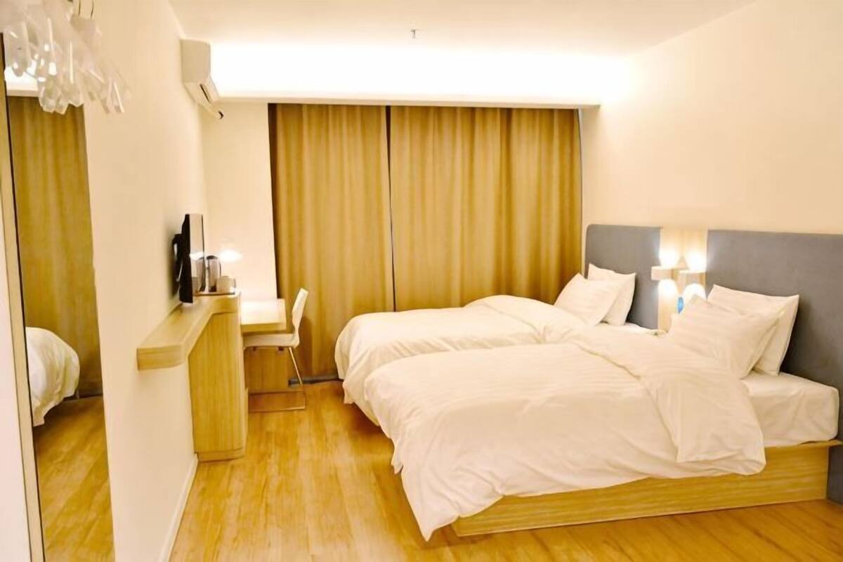 Une chambre d’hôtel avec un lit, des tables de chevet, un bureau et une chaise.