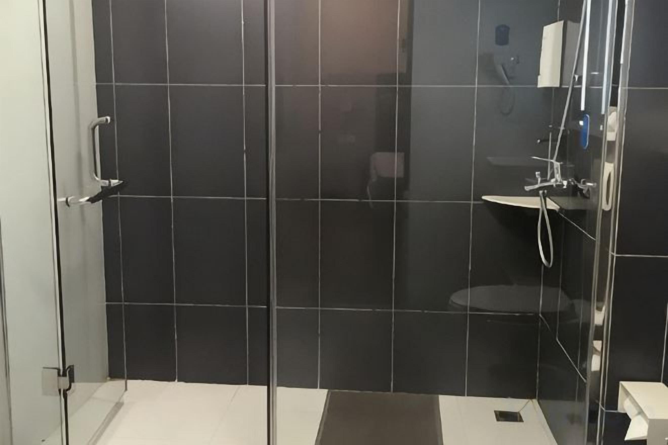 A bathroom with a glass shower enclosure, a white sink, and a toilet.