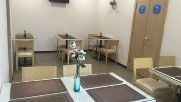 Une chambre d’hôtel avec un coin repas, un téléviseur fixé au mur et une porte en bois avec une pancarte.
