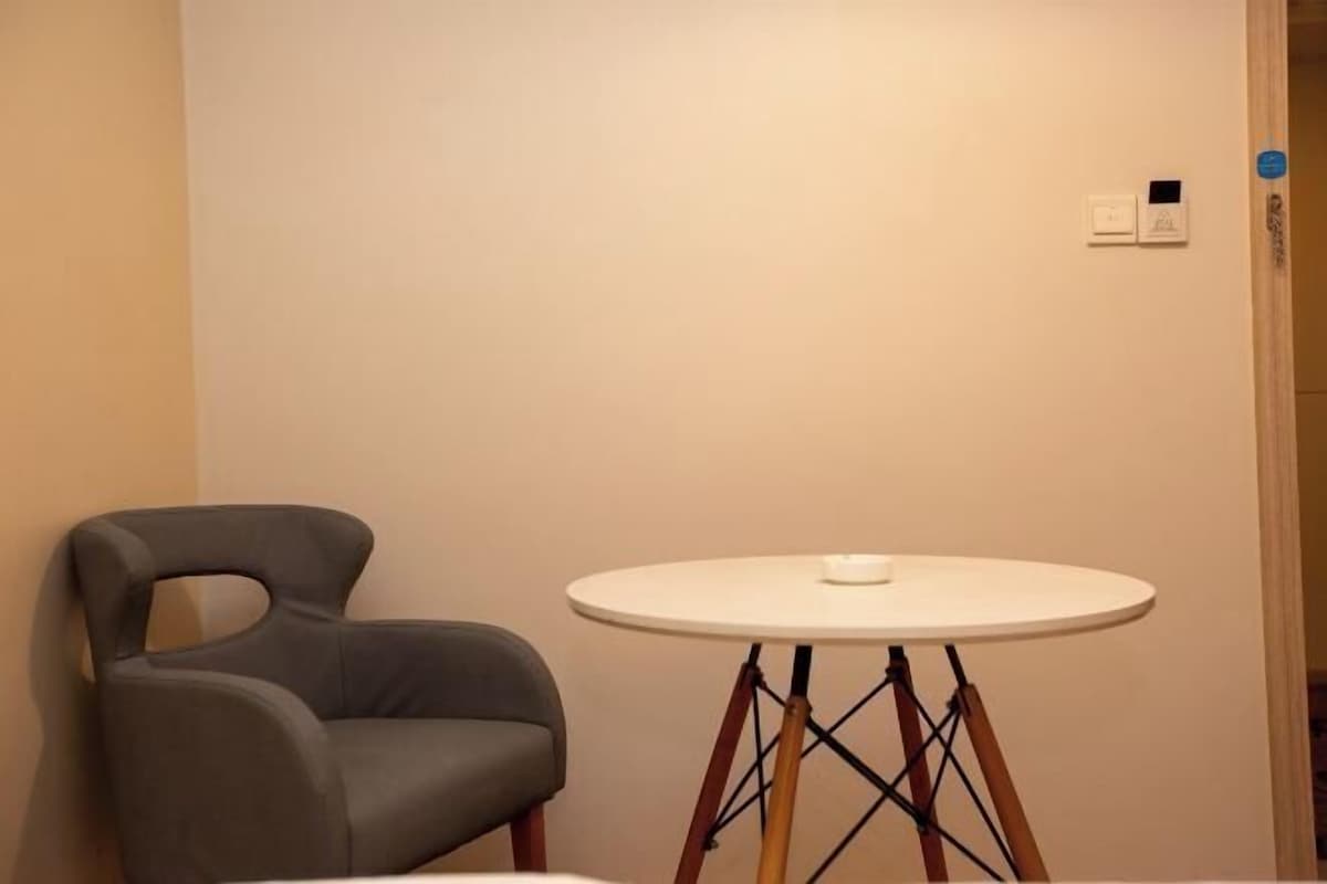 A room with a round table, a modern chair, and a wall-mounted light switch.