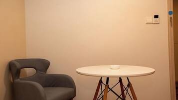 A room with a round table, a modern chair, and a wall-mounted light switch.