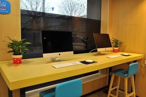 Un mostrador de recepción con dos monitores, un teclado y un ratón. Hay dos plantas en macetas a cada lado del mostrador.