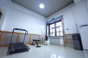 A gym with a treadmill, bench, and exercise equipment.