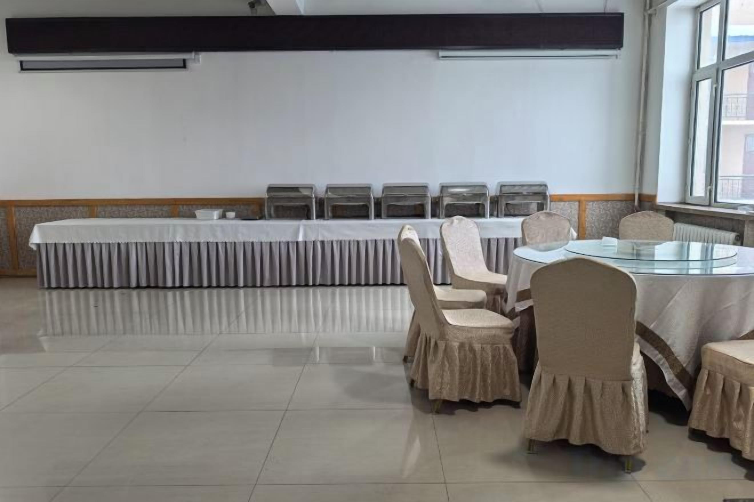 A conference room with a long table and chairs, a round table with chairs, and a window providing natural light.
