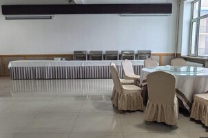 Una sala de conferencias con una mesa larga y sillas, una mesa redonda con sillas, y un ventanal que proporciona luz natural.