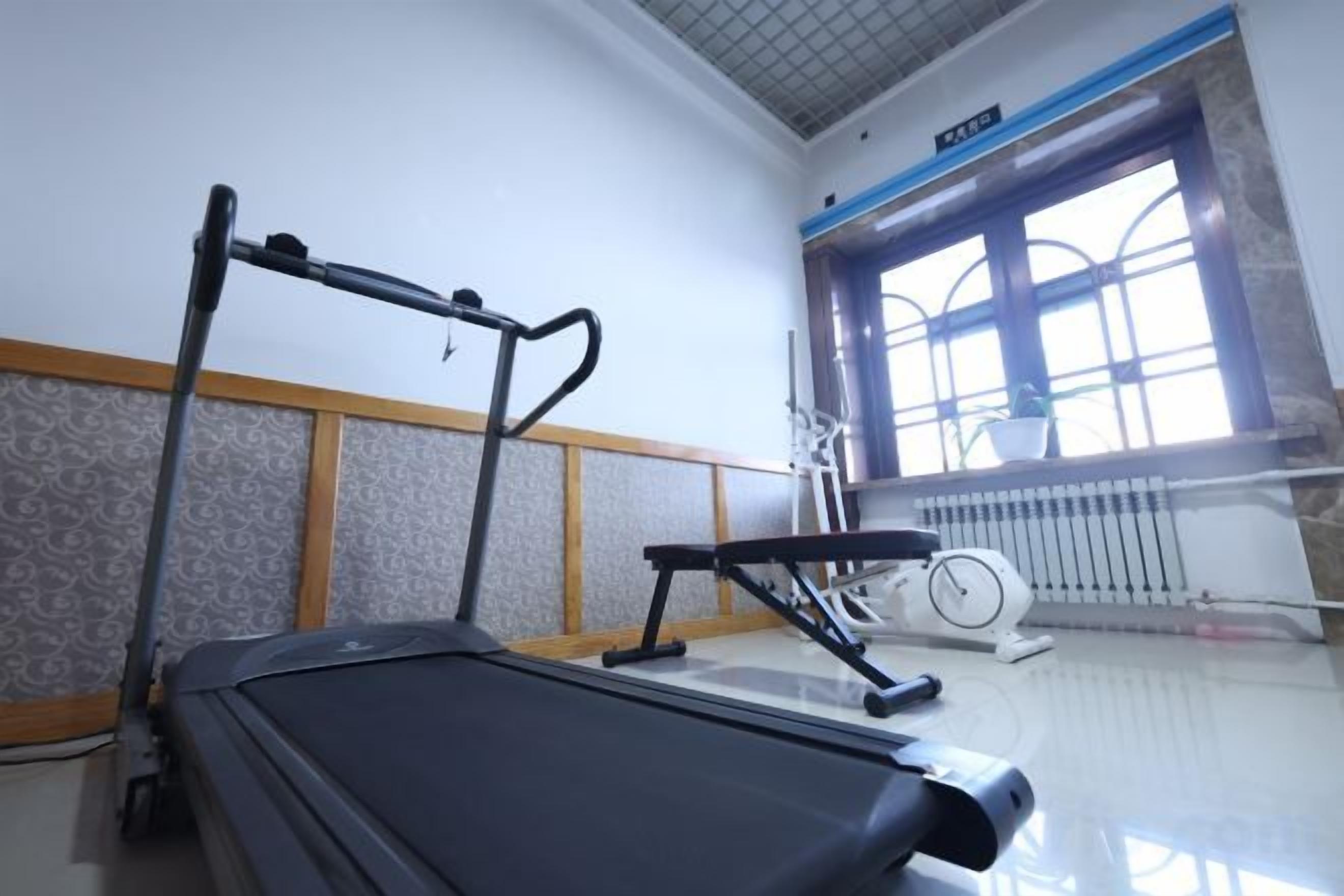 Un gimnasio con cinta de correr, equipo de ejercicio y un ventanal con vistas.