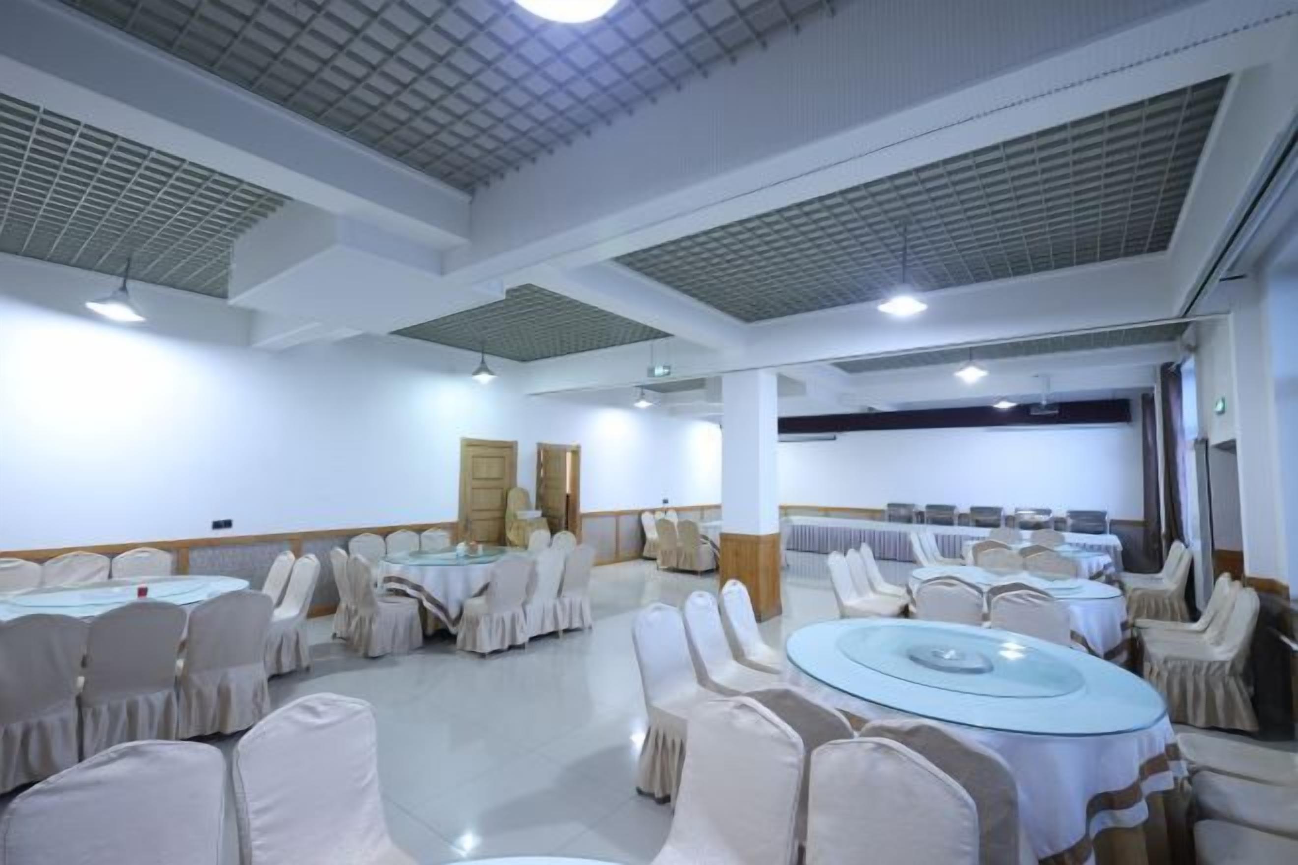 A conference room with round tables and chairs, white walls, and a ceiling with grid-like patterns.