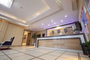 Zona de recepción de un hotel con mostrador, un reloj y una sala de espera.