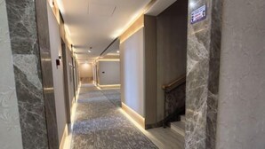 Ein Hotelgang mit Marmorwänden, Marmorboden und einem Schild, das den Weg zur Lobby weist.