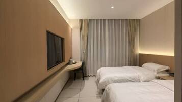 A hotel room with two beds, a desk, a chair, and a large window.