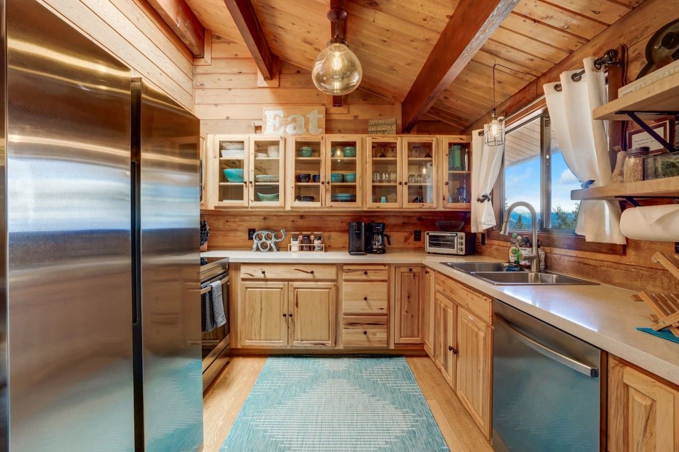 Una cocina con armarios de madera, un refrigerador de acero inoxidable y una alfombra azul.