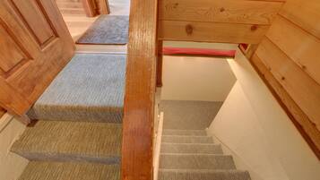 Un escalier en bois, dont les marches sont recouvertes de moquette, mène à un palier.