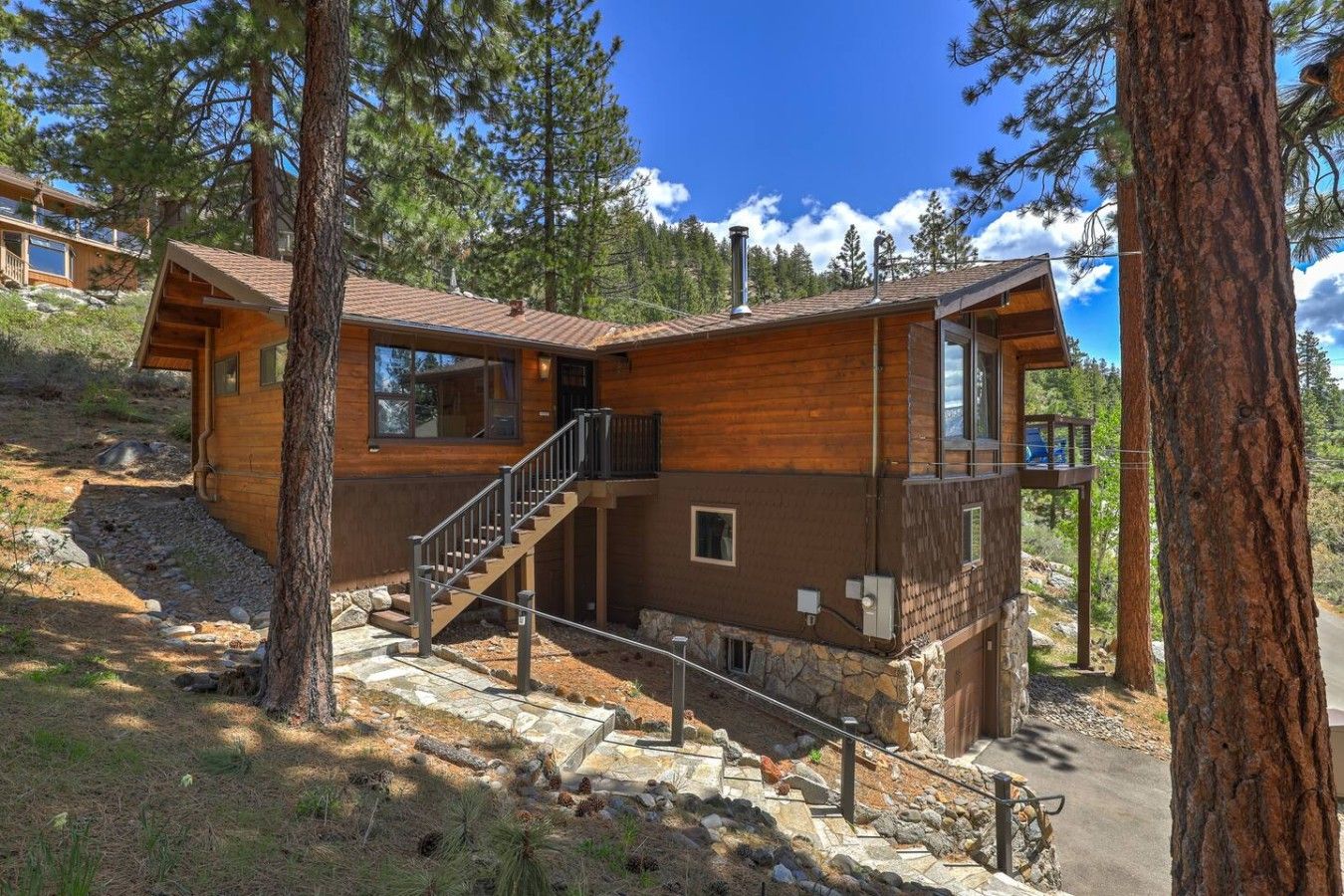 A cabin with a wooden exterior, a staircase leading to a deck, and a clear sky.