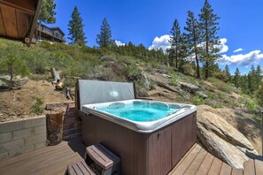 A hot tub on a wooden deck with a mountainous backdrop.