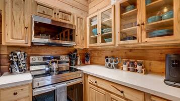 Una cocina con armarios de madera, electrodomésticos de acero inoxidable y una encimera con diversos utensilios de cocina.