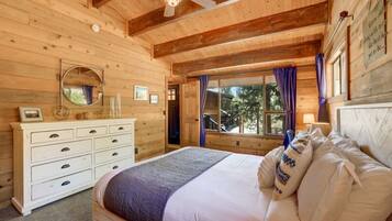 Un dormitorio de cabaña de madera con cama, cómoda y ventana con cortinas.