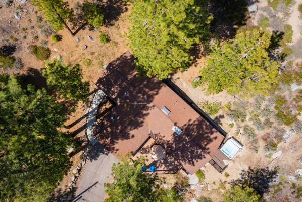 An aerial view of a property with a central building, surrounded by trees and a paved area.
