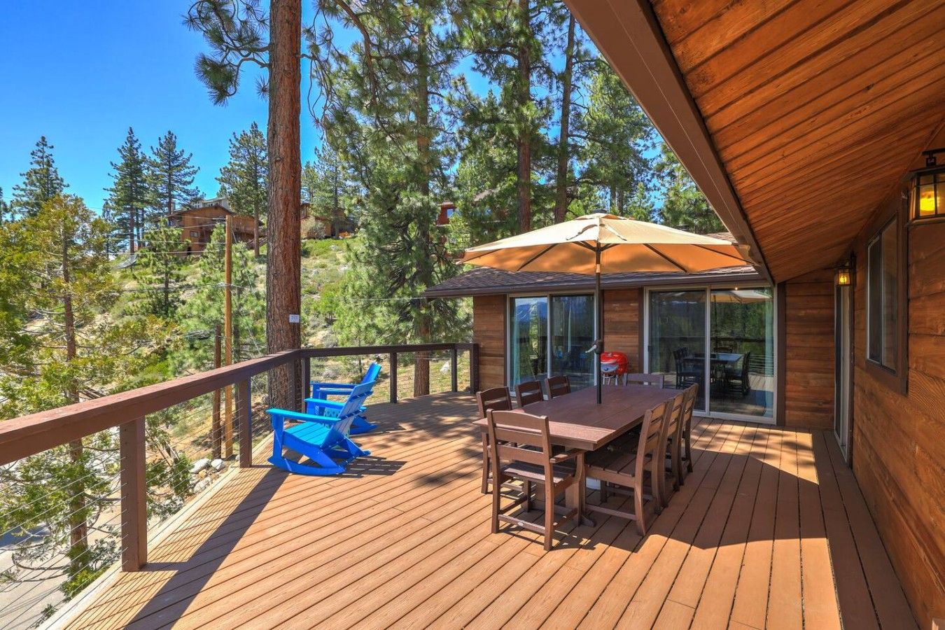 A wooden deck with outdoor furniture, a barbecue grill, and a glass door leading to a covered area.