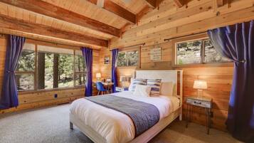 Ein Schlafzimmer einer Holzhütte mit einem Bett, einem Schreibtisch und einem Stuhl.