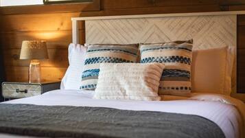 A bed with a white headboard, two pillows with blue and white patterns, and a gray blanket.