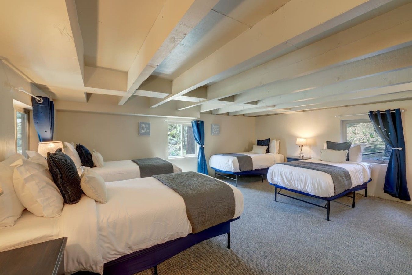 Une chambre d’hôtel avec deux lits, un bureau et une fenêtre avec des rideaux.