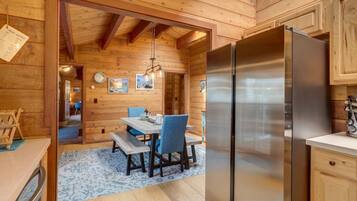 Un interior de madera con comedor, refrigerador de acero inoxidable y techo de madera.