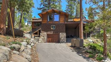 Eine zweistöckige Holzhütte mit Steinfundament, Garage und überdachter Veranda.
