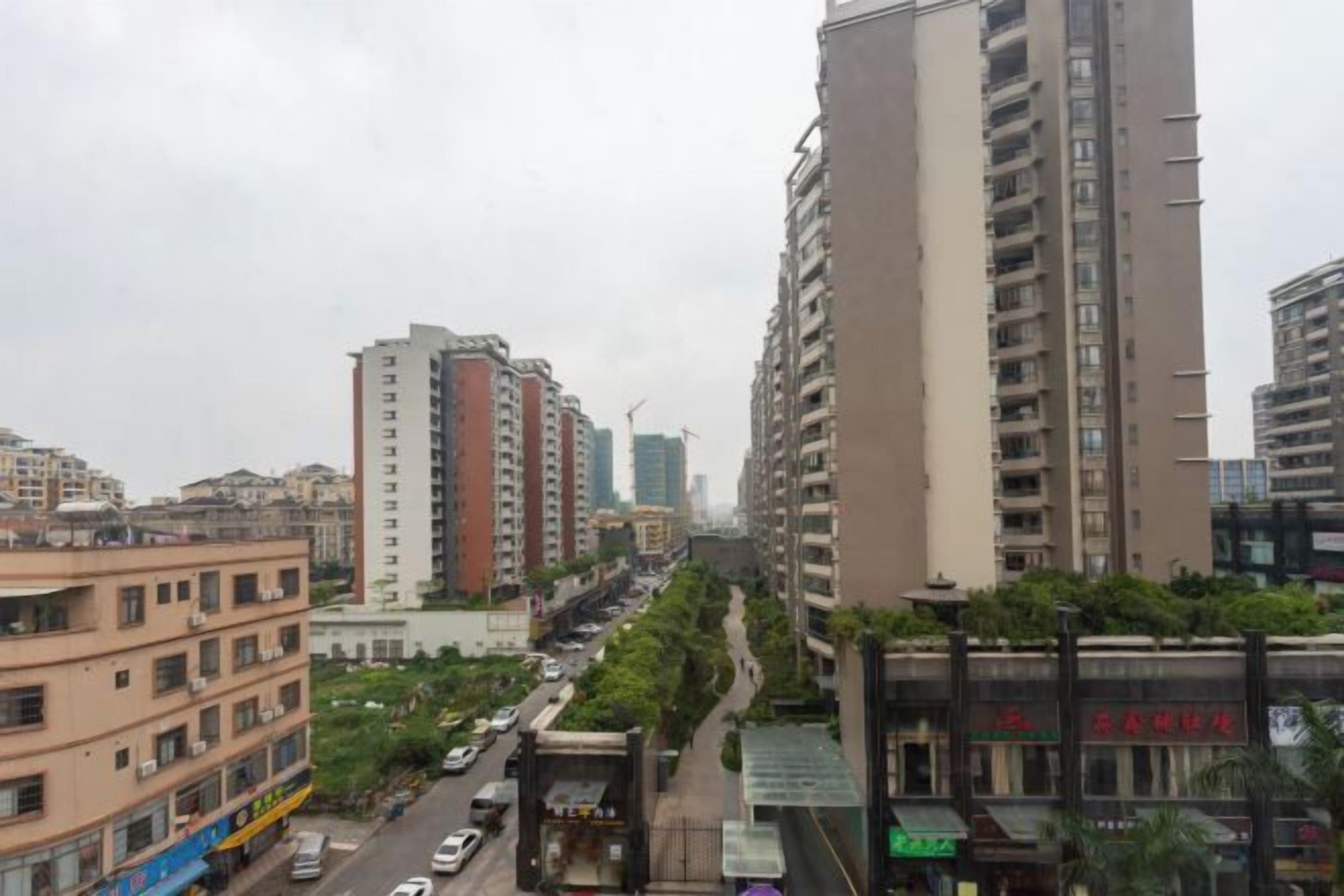 A cityscape with high-rise buildings, a road with vehicles, and a pedestrian walkway.