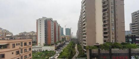 A cityscape with high-rise buildings, a road with vehicles, and a pedestrian walkway.
