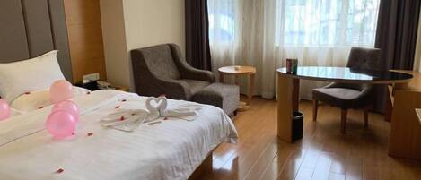 A hotel room with a bed, two armchairs, a small table, and a window with curtains.