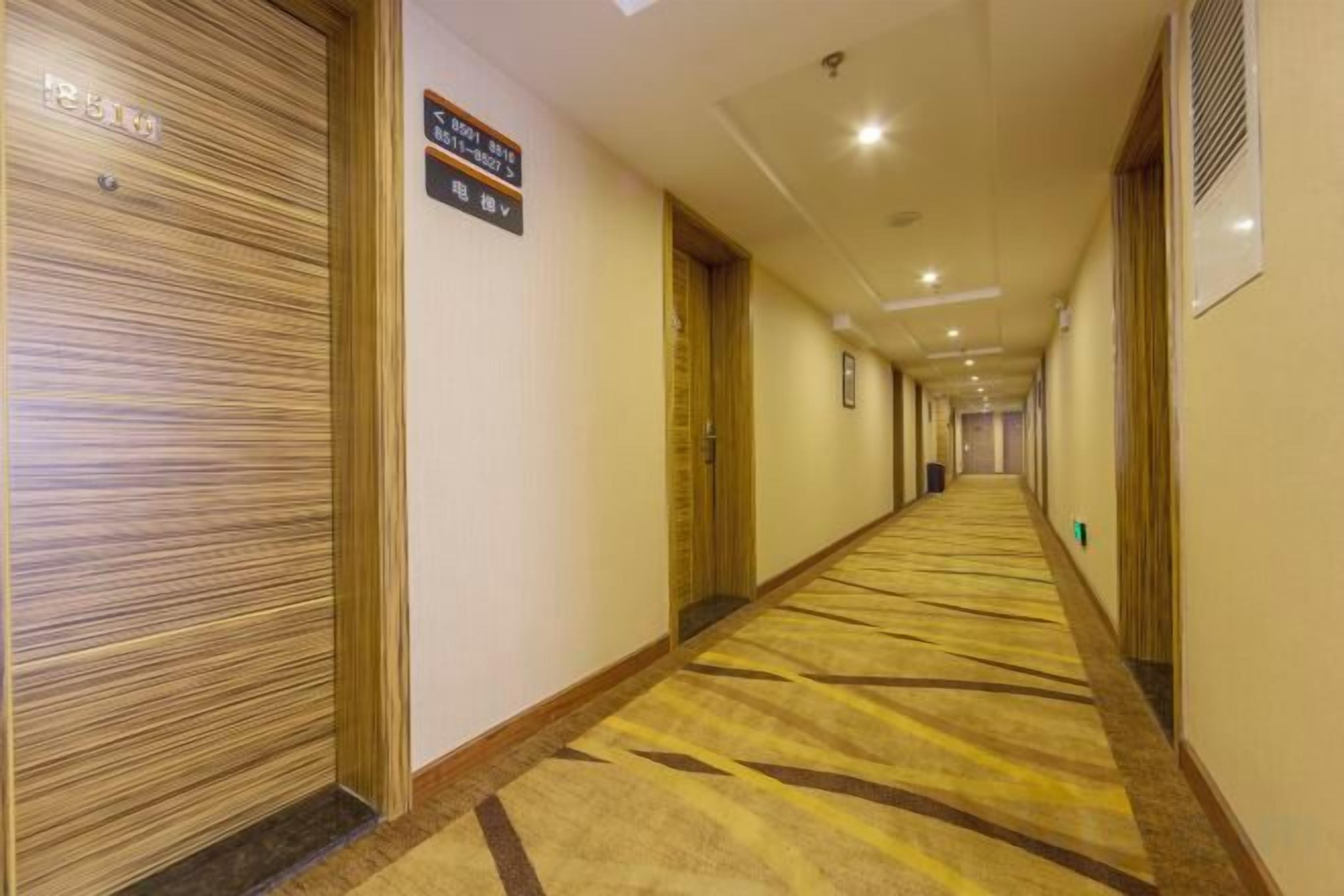 A hotel hallway with closed doors, a carpeted floor, and a sign indicating room availability.