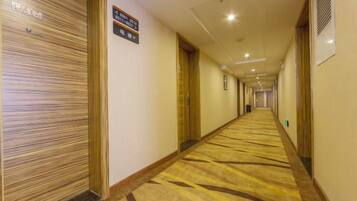 A hotel hallway with closed doors, a carpeted floor, and a sign indicating room availability.