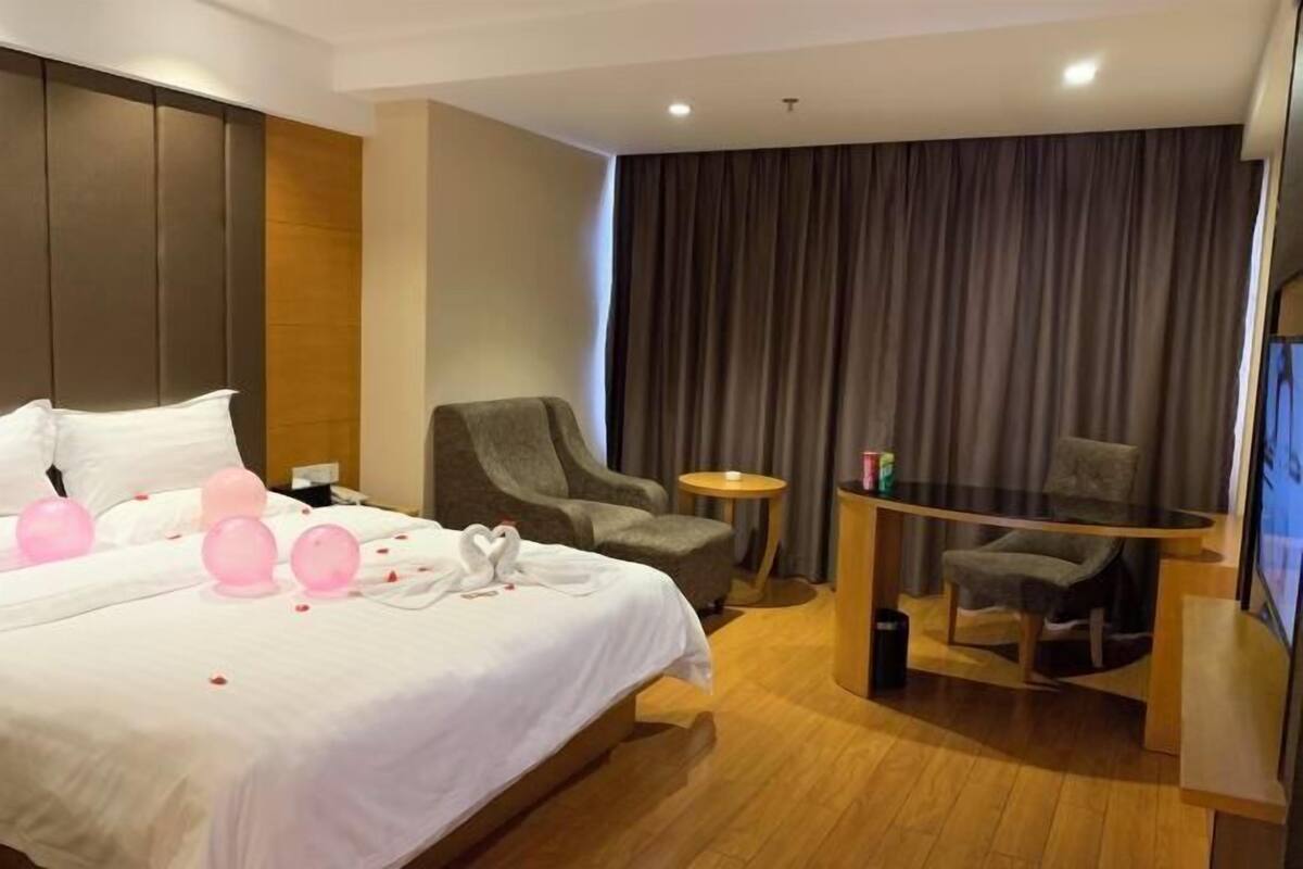 Una habitación de hotel con cama, dos sillones, una mesita y televisor.