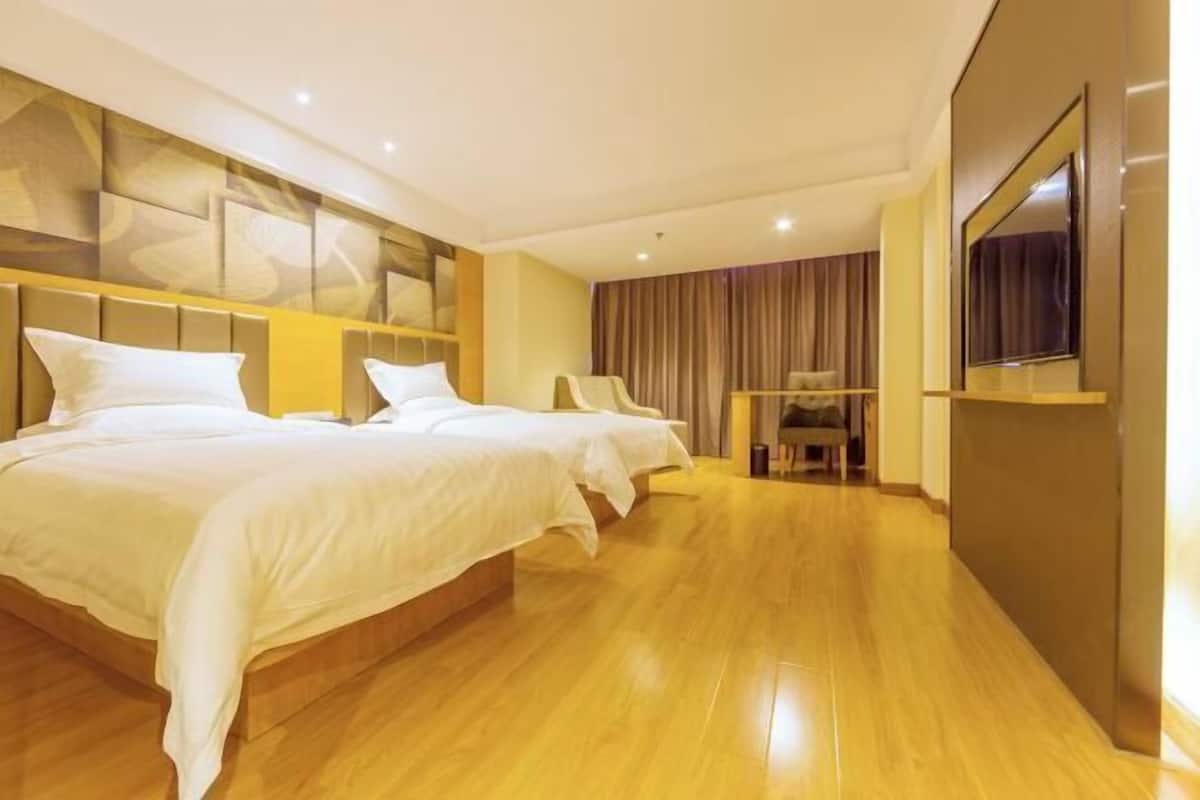 Habitación de hotel con dos camas, un escritorio y una televisión.