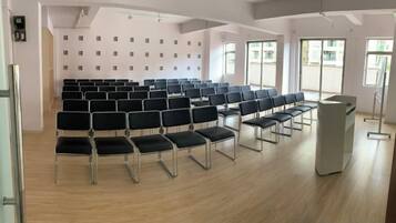 A conference room with rows of chairs, a podium, and large windows.