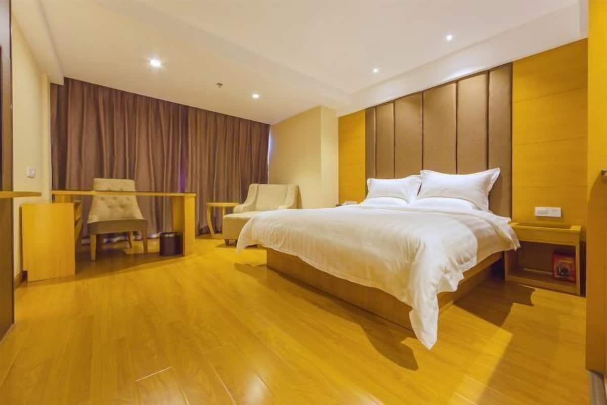 Una habitación de hotel moderna con una cama grande, un escritorio, una silla y un telón de fondo.
