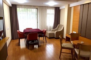 A hotel room with a dining table, chairs, a sofa, and a TV. - Xingyun Hotel (Zhongshan Shaxi Xingbao Times Square) (Zhongshan)